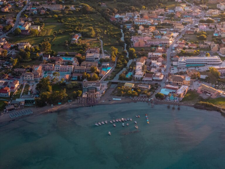 Stunning aerial photo showcasing a coastal village with vibrant buildings and boats at sunset in Corfu, Greece.